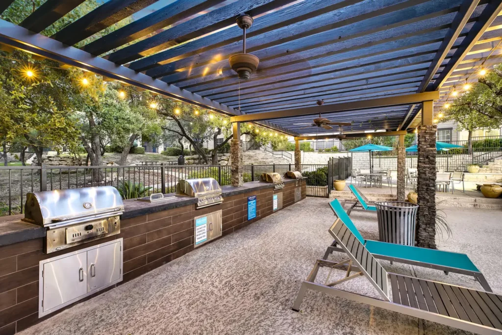 Covered swimming pool desk with outdoor lounge seating, lights, and grills