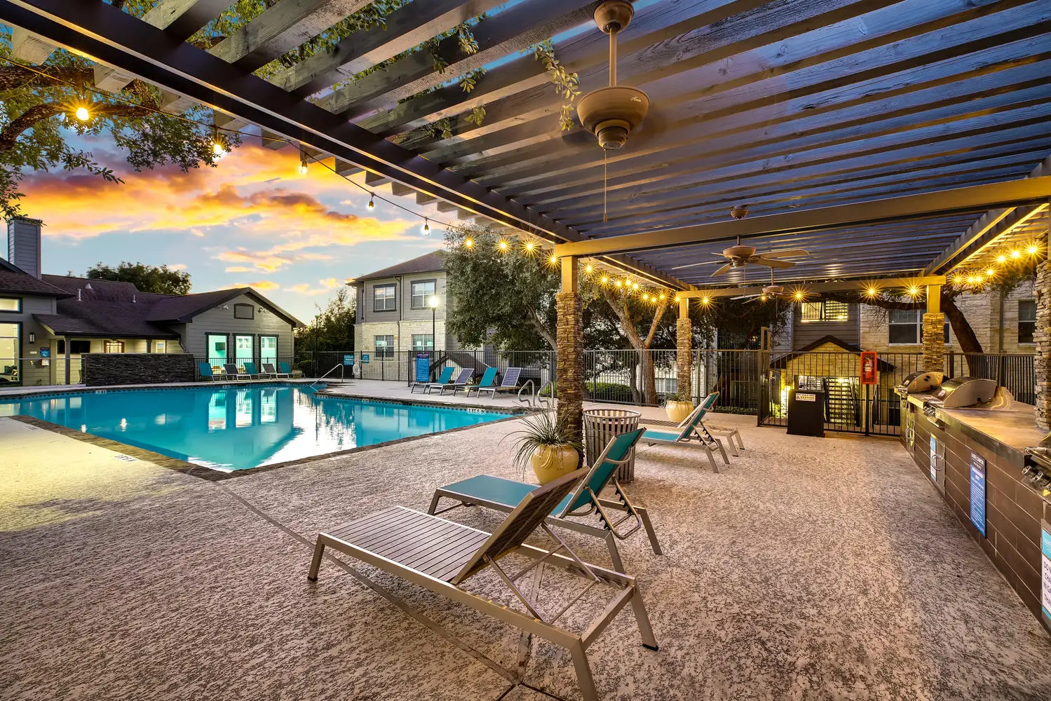 Covered swimming pool desk with outdoor lounge seating, lights, and grills