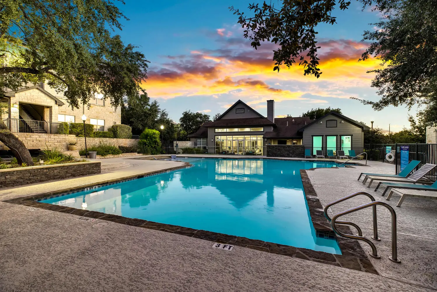 Swimming pool with outdoor lounge seating, lights, and trees