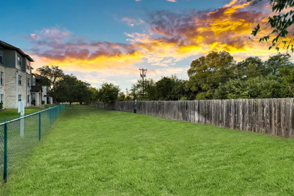Fenced, grassy dog park with bench and signage