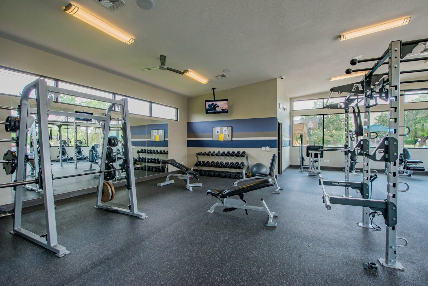 Large fitness studio with ceiling fan, tv, and lots of equipment of many types