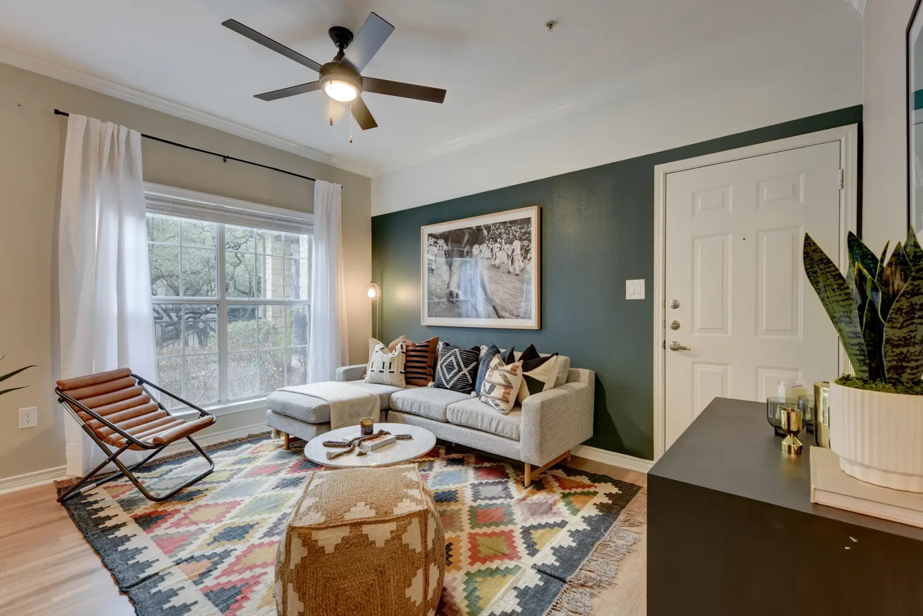 Living room near the kitchen with a ceiling fan, wood-style flooring, and a window